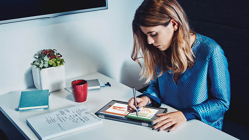 Woman writing on tablet while sitting at a table